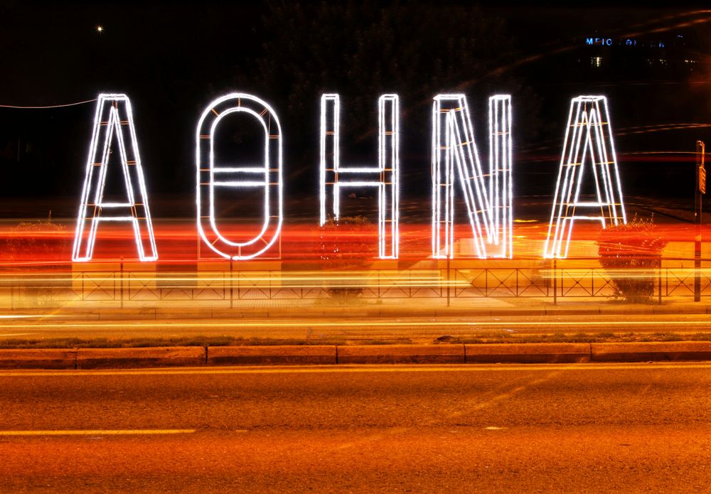 Leuchtender Schriftzug ATHINA an einer Straße in Athen bei Nacht